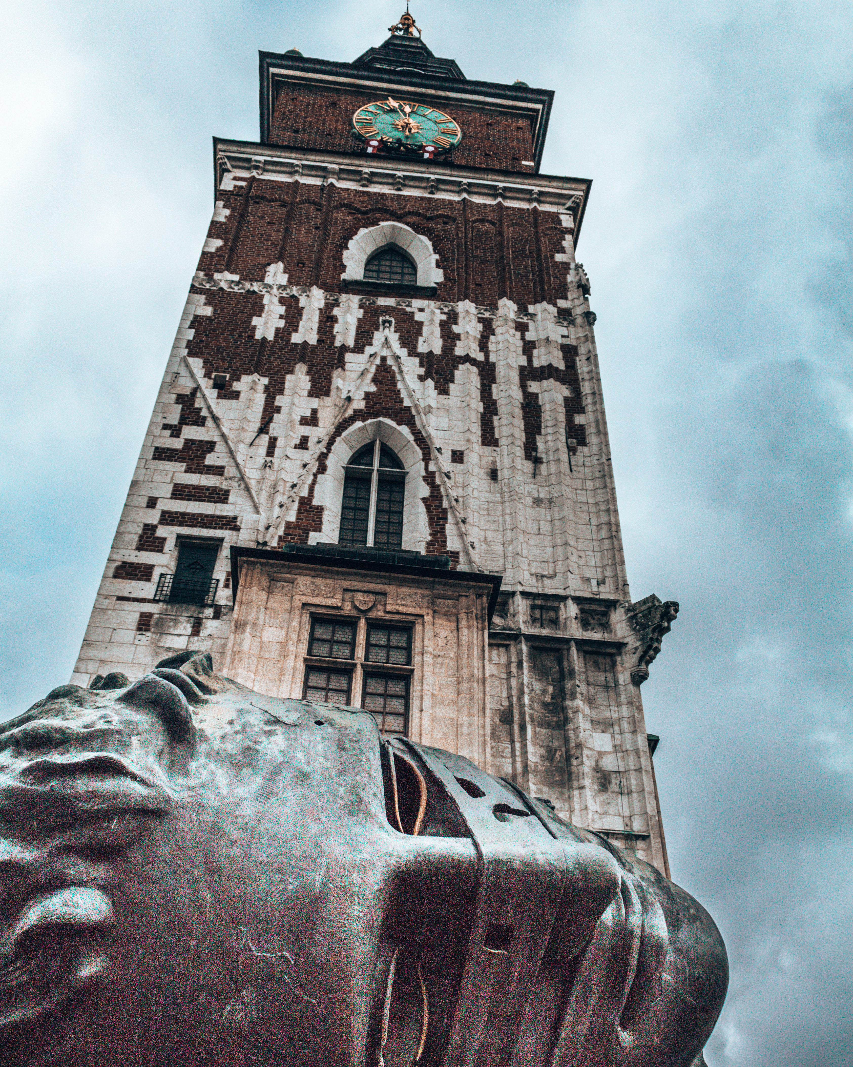 The Town Hall Tower and a sculpture of a head in the old town of Krakow, Poland